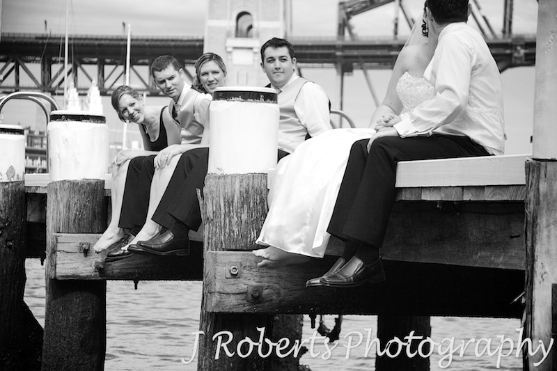 Bridal party looking at couple kissing on pier - wedding photography sydney